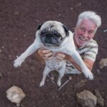 homme qui porte un carlin